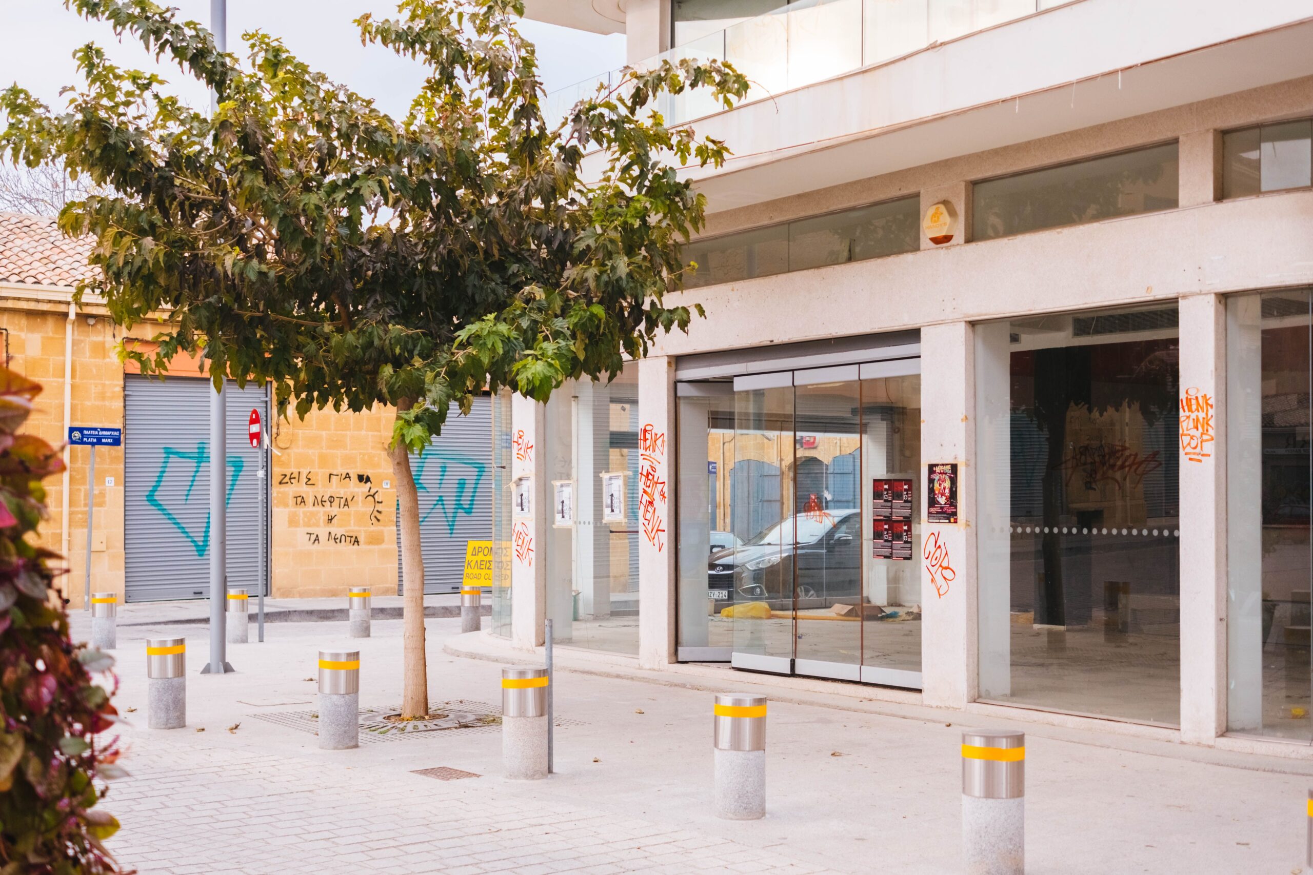 Services A modern commercial building exterior with glass doors and urban graffiti, street view.