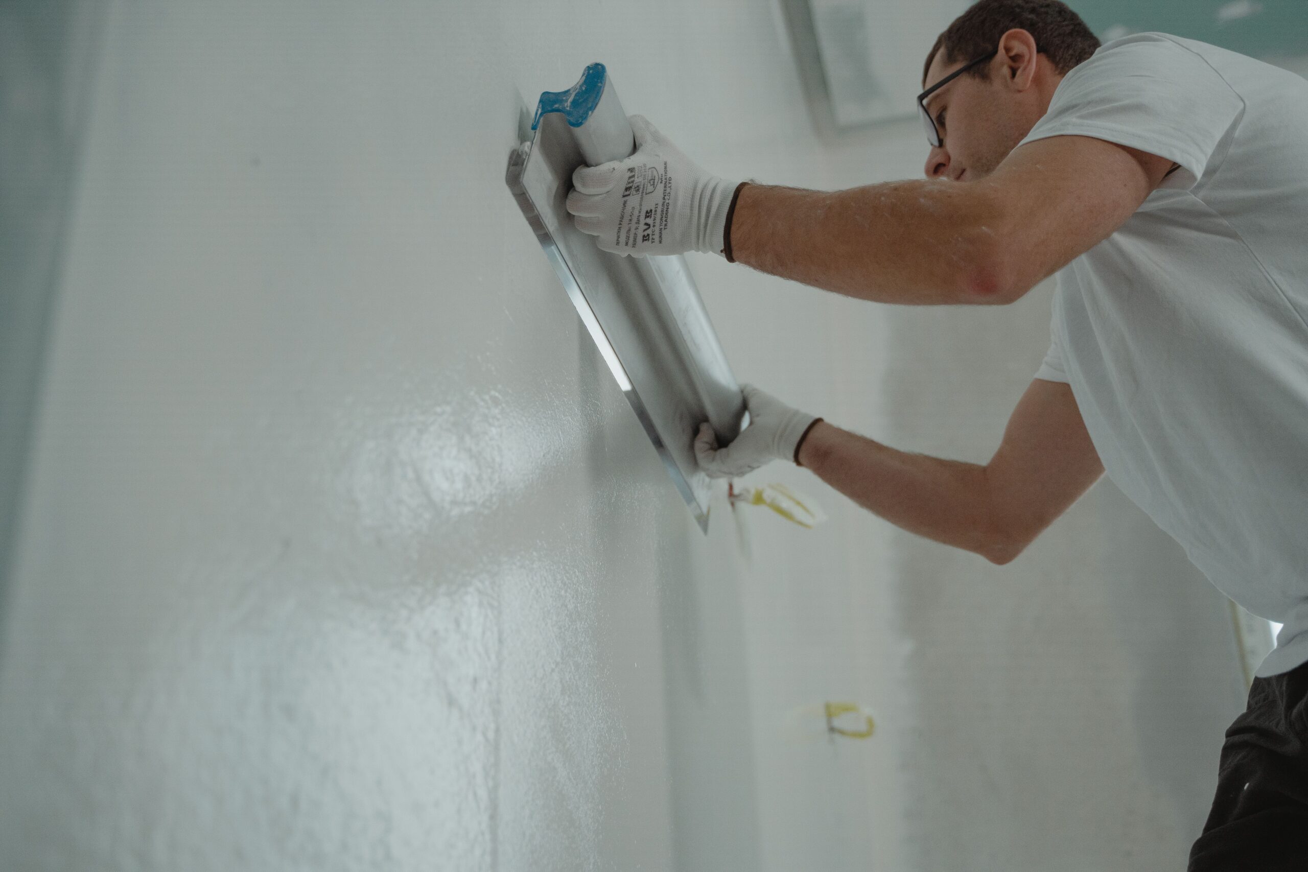 Services A man works on home renovation, applying plaster to an interior wall for a smooth finish.